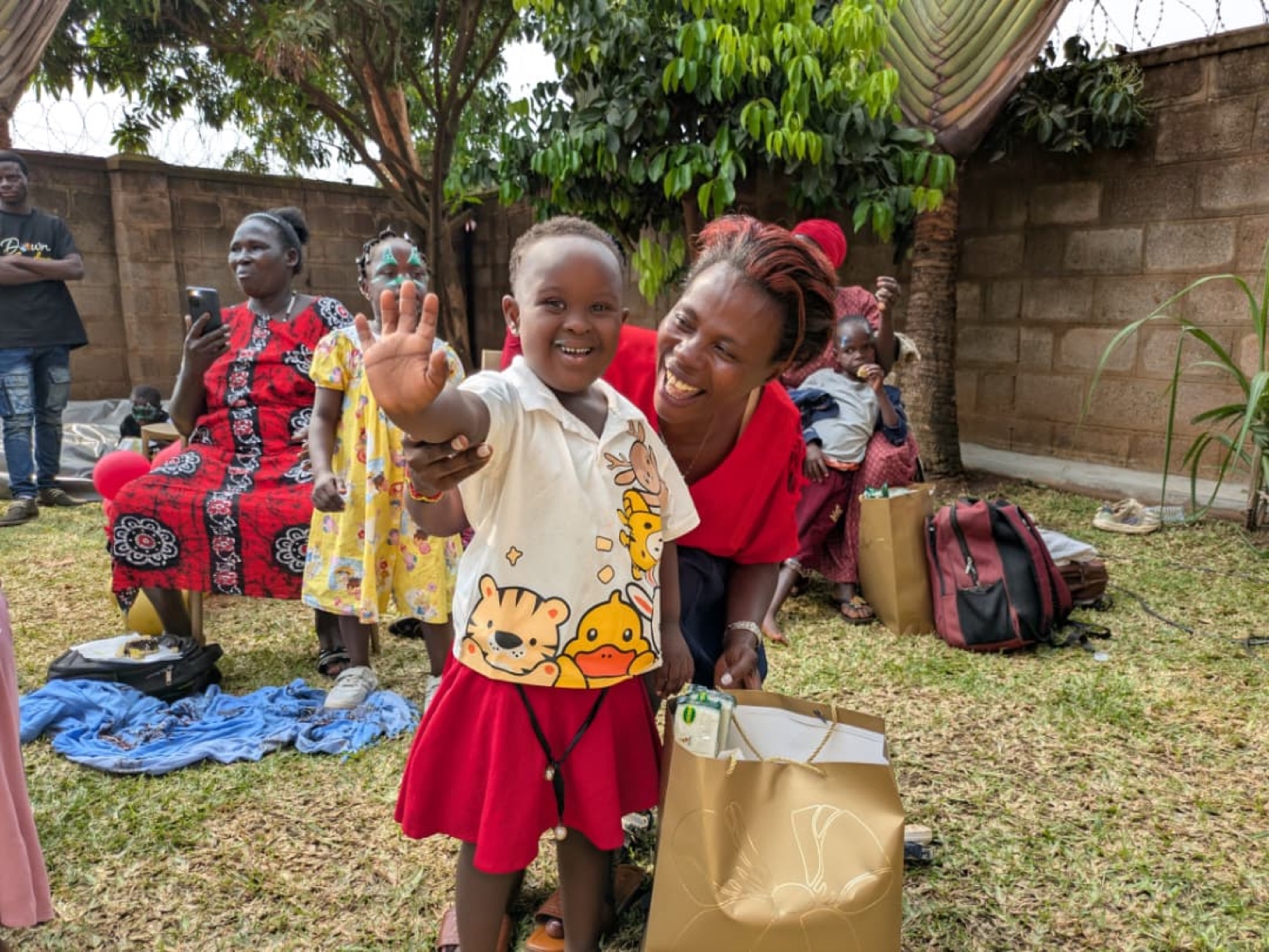 A smiling child waves during a Down Syndrome Centre community celebration.